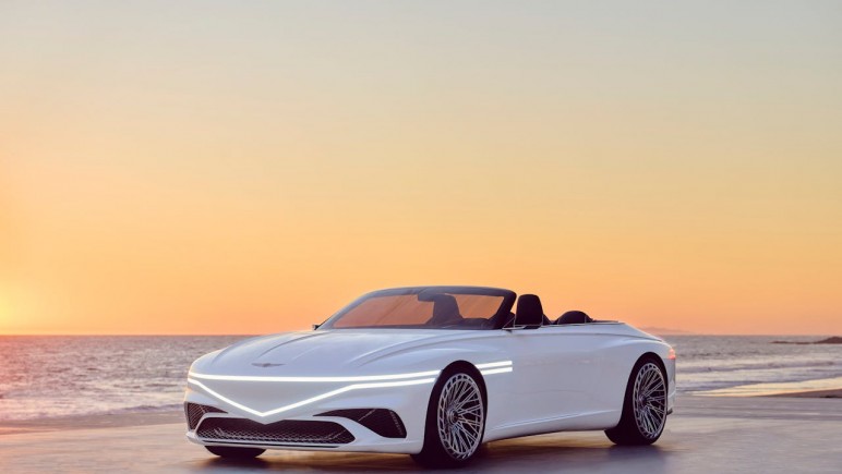 WHITE GENESIS CAR ON THE SHORE OF A BEACH UNDER GOLDEN SKY