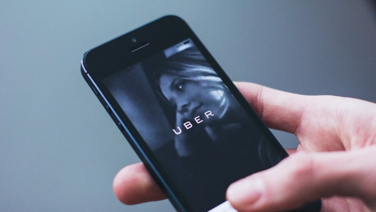 PERSON HOLDING SMARTPHONE  WITH UBER LOGO