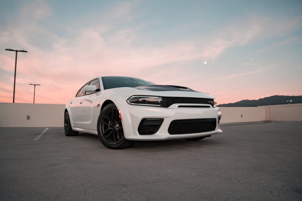 WHITE DODGE CHARGER SRT HELLCAT WIDEBODY ON THE TOP FLOOR OF THE PARKING GARAGE AT DUSK