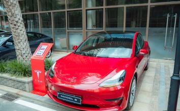 RED TESLA CAR PARKED OUTSIDE A BUILDING