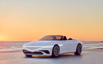 WHITE GENESIS CAR ON THE SHORE OF A BEACH UNDER GOLDEN SKY