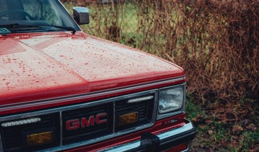 RED CLASSIC GMC JIMMY CAR COVERED WITH RAIN DROPS