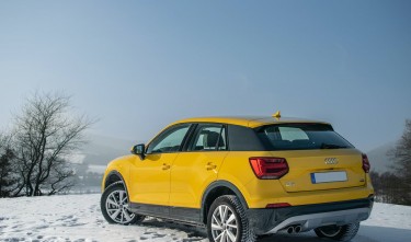 A YELLOW AUDI CAR PARKED ON A SNOW COVERED GROUND