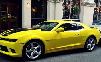 YELLOW CHEVROLET CAMARO PARKED OUTSIDE BUILDING