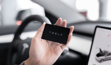 PERSON HOLDING A BLACK CARD TESLA